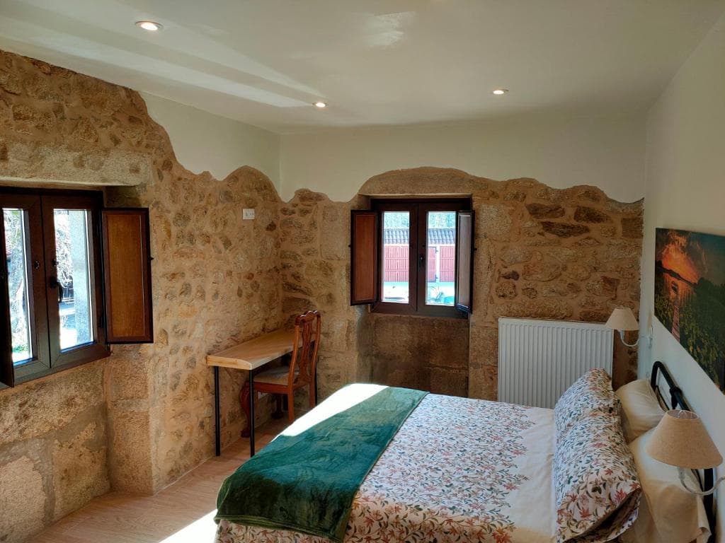 Habitación Castaño con muro de piedra y cama de matrimonio