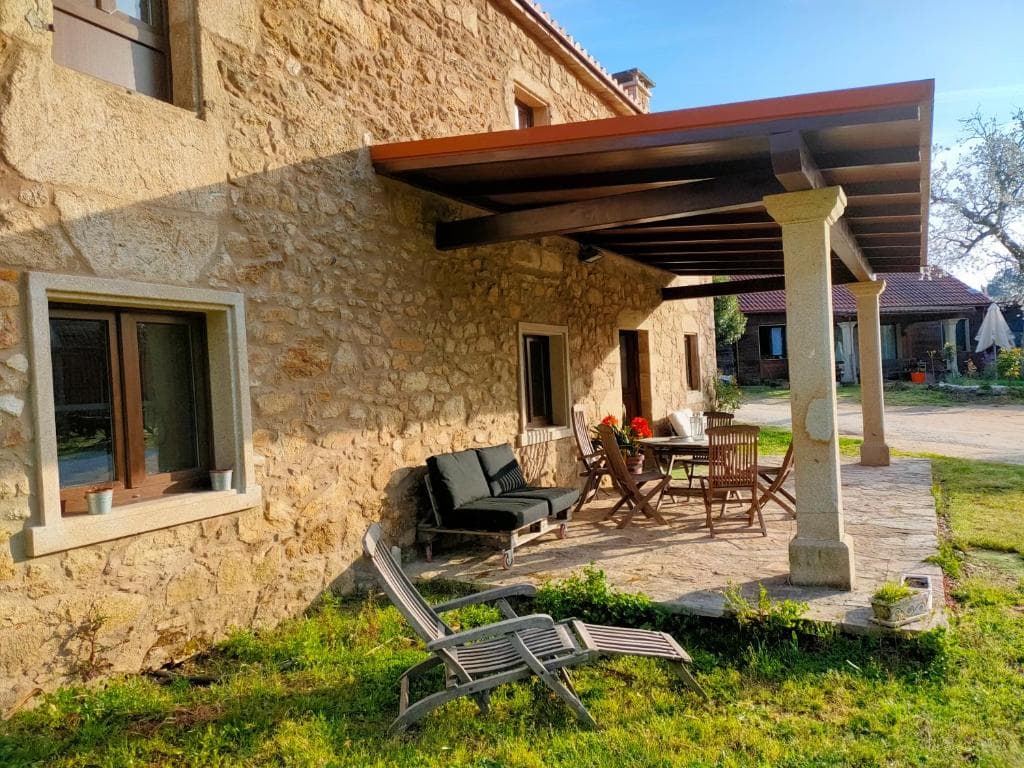Porche de piedra con pérgola y mobiliario de jardín en O Rincón de Esther